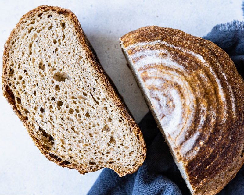 Un pain Piaf sans gluten coupé en deux. On voit la mie bien alvéolée et la croûte dorée.